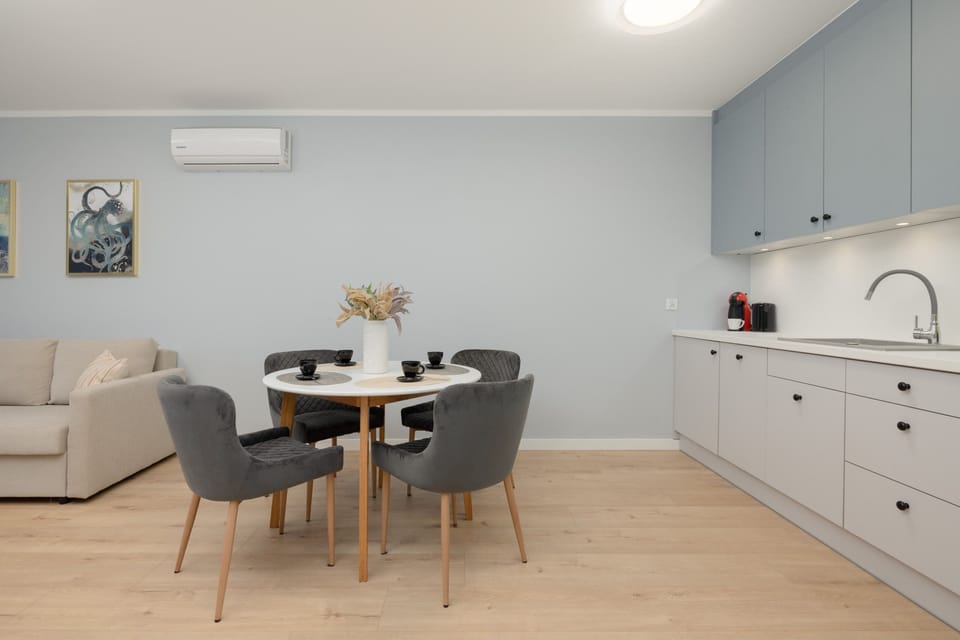 A view of the combined living and dining areas, with a comfortable sofa, dining table, and kitchenette in the background.