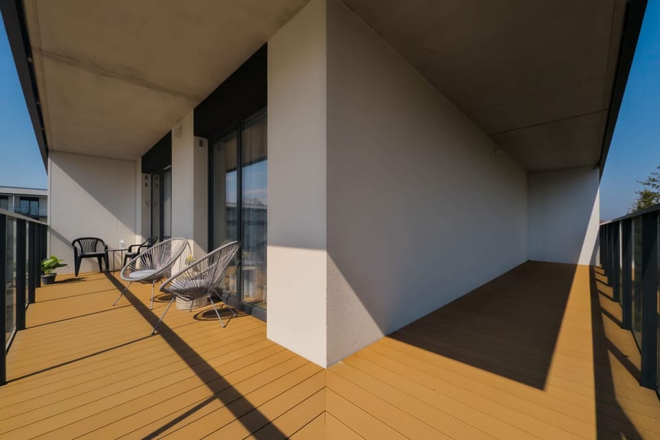 A private balcony equipped with modern outdoor chairs, overlooking a peaceful forest landscape.