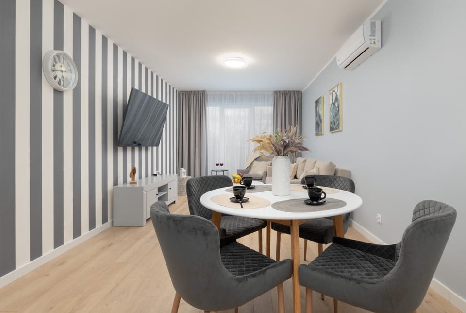 A stylish living space with a striped accent wall, a beige sofa, a flat-screen TV, and modern decor.