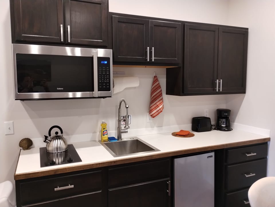 Leisure Suite - Kitchen Equipped with Cooking Essentials including  4-Cup Drip Coffee Maker, Filters, Coffee, Tea, Creamer, and Sugar.
