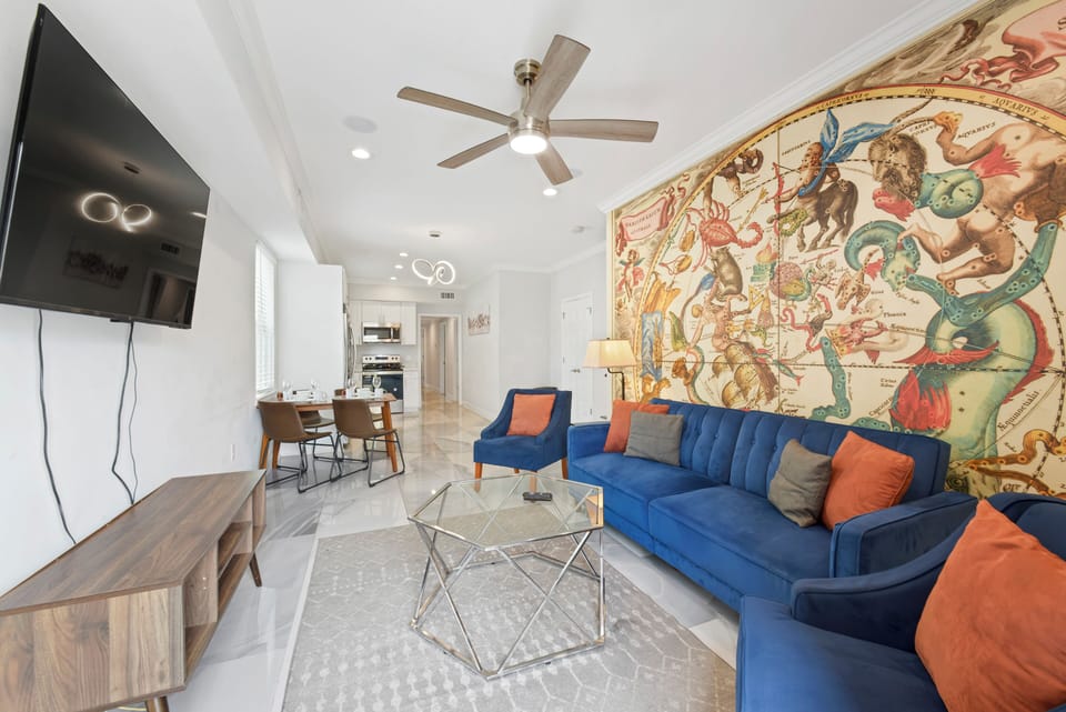 Living Room- stylish sofa and chairs, wall mounted smart TV, overhead fan remote