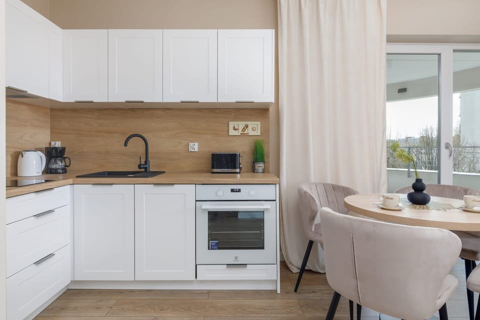 A different perspective of the kitchen, showing the built-in appliances, a sink, and a window that allows for natural light. The white and wood combination adds warmth to the space.