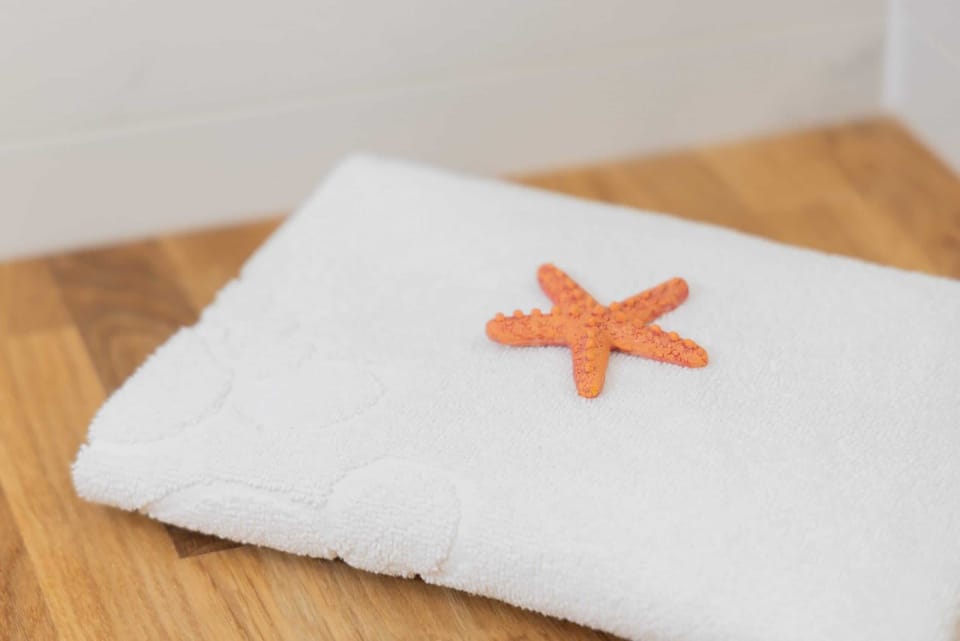 A close-up of a soft white towel decorated with a starfish, adding a touch of luxury and care for guests.

