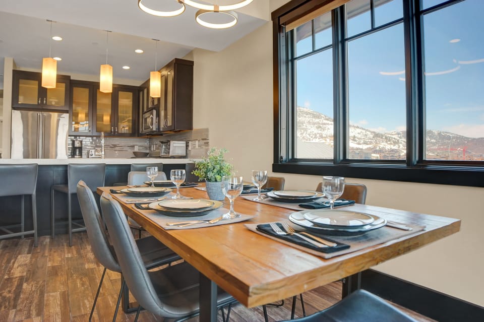 Wood dining table with seating for 6 next to a window with mountain views