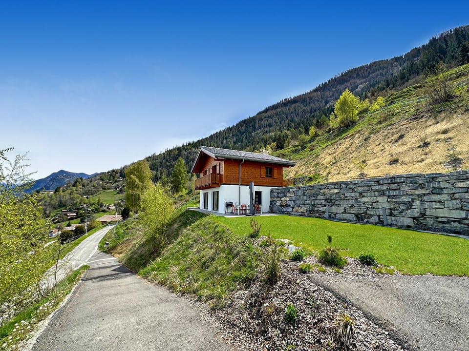 View of the splendid My Mountain Paradise chalet, with its summery outdoor layout, parasol-shaded dining table and barbecue area.