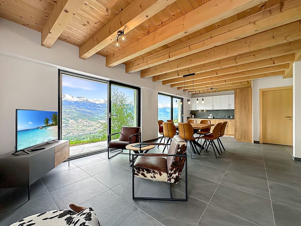 Living room with TV and large picture window offering spectacular views, opening onto the spacious dining room.