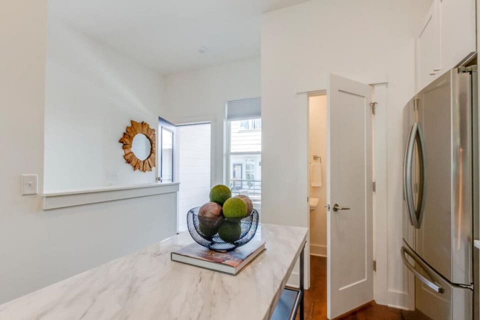 Entryway with marble console, decorative bowl, round gold mirror, and white walls