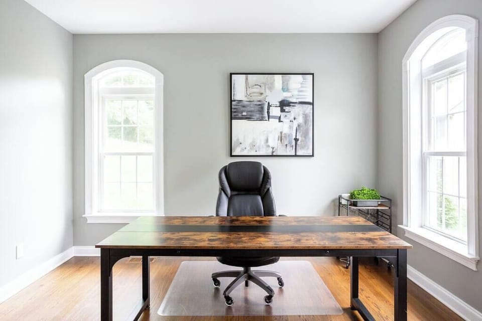 Private office with large desk, office chair, arched windows, and natural light.
