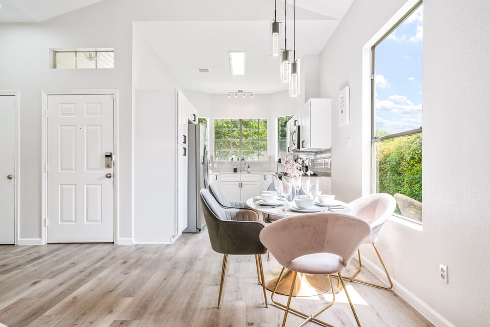 mid-century oval shaped modern dining table set with six grey and blush chairs.