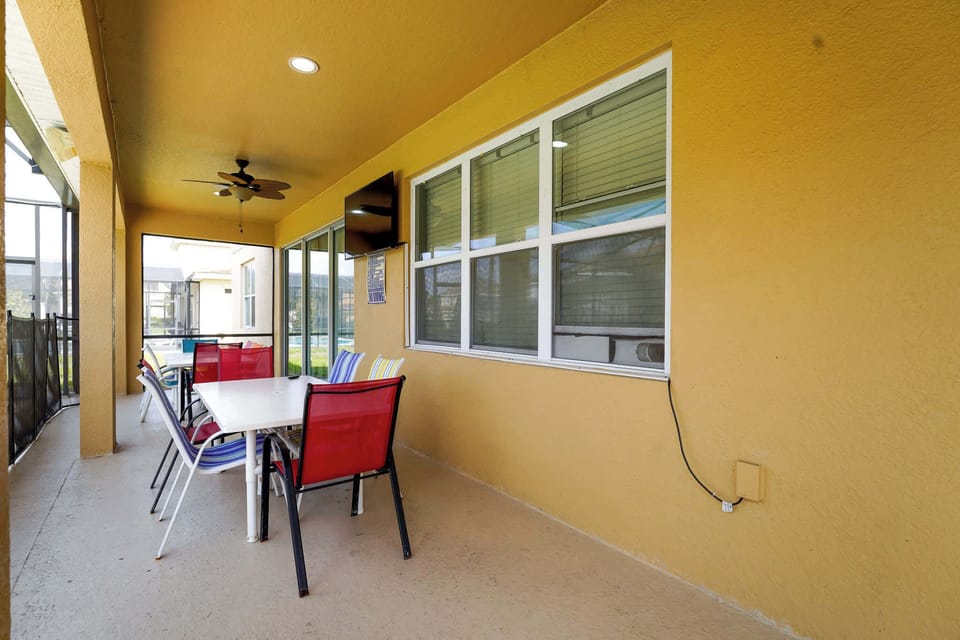 Relax on the vibrant patio with a TV and ceiling fan, perfect for outdoor dining and entertainment.