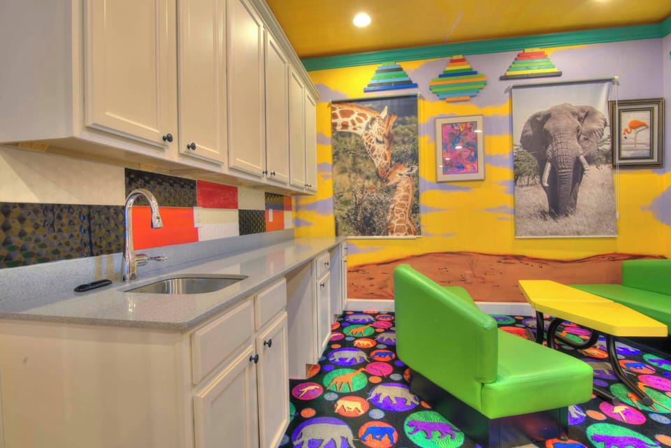 Explore a vibrant safari-themed room with playful decor and a convenient kitchenette, perfect for family fun.