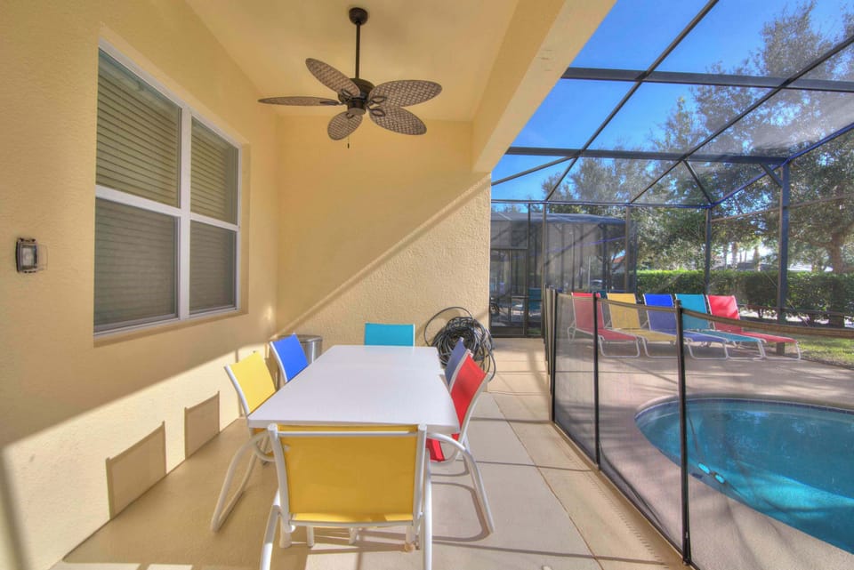 Enjoy vibrant outdoor dining and relaxation by the pool in this sunny screened patio.