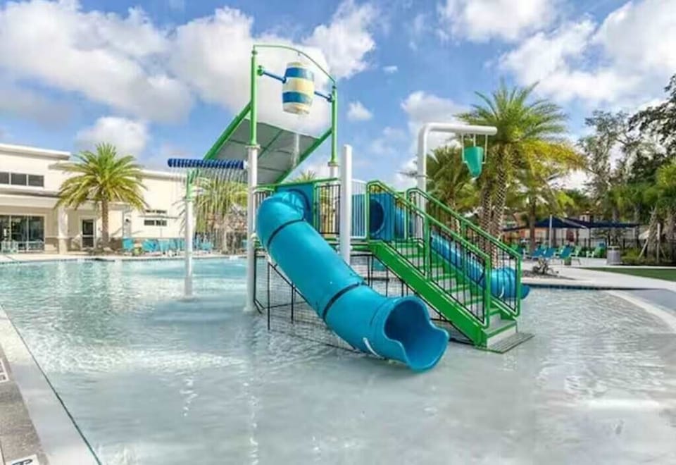 Dive into fun at this vibrant pool with a thrilling water slide, perfect for family enjoyment and relaxation under the palm trees.