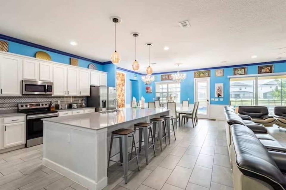 Entertain in style with this expansive kitchen featuring a large island, modern appliances, and vibrant decor, perfect for group gatherings.