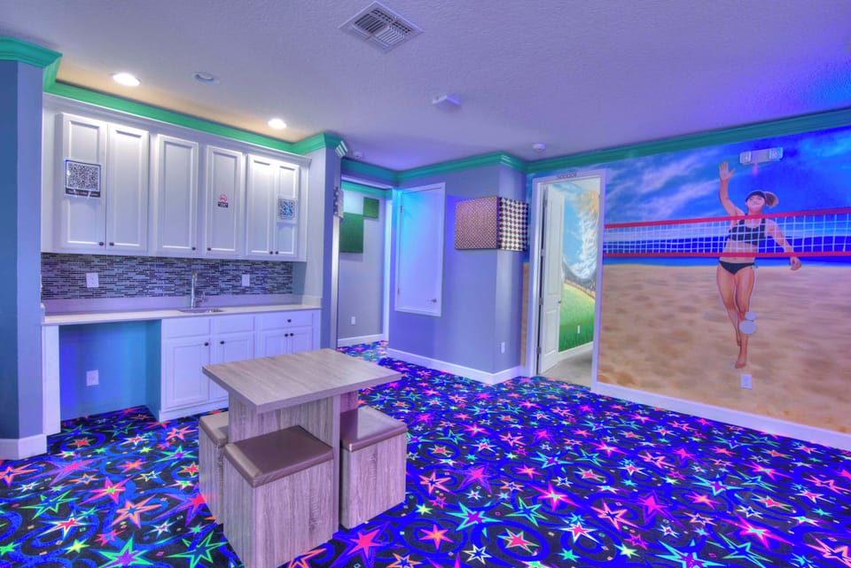 Experience fun and excitement in this vibrant game room with a unique volleyball mural and convenient kitchenette.