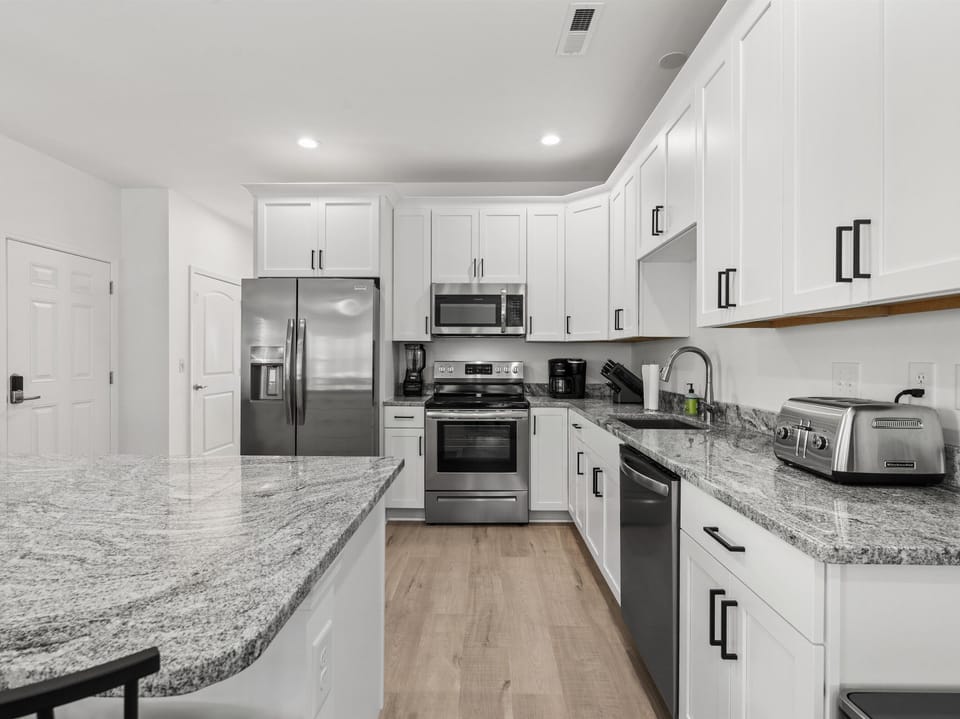 Your spacious kitchen features gleaming granite countertops, stainless steel appliances, and pristine white cabinets—perfect for preparing memorable meals during your stay.