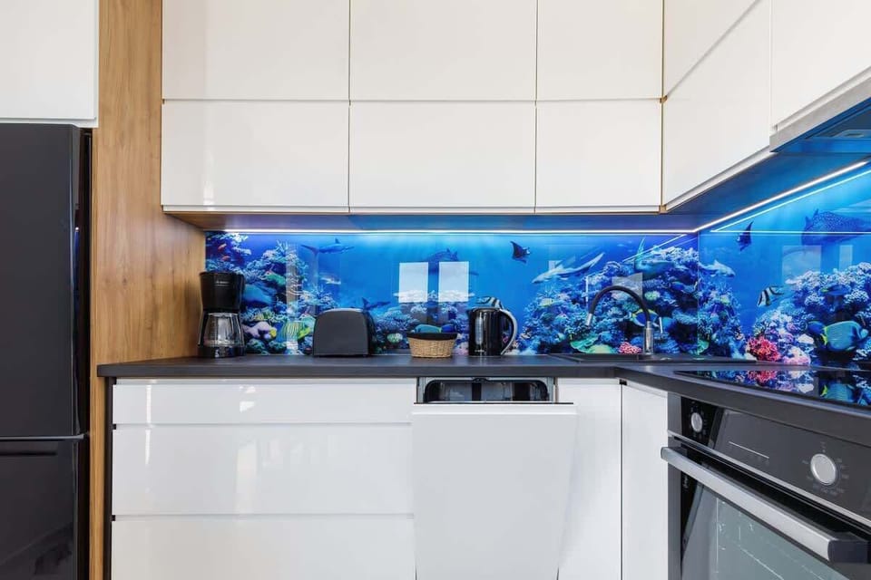 A stylish kitchen with white cabinets, wooden finishes, and a vibrant aquarium-themed backsplash.
