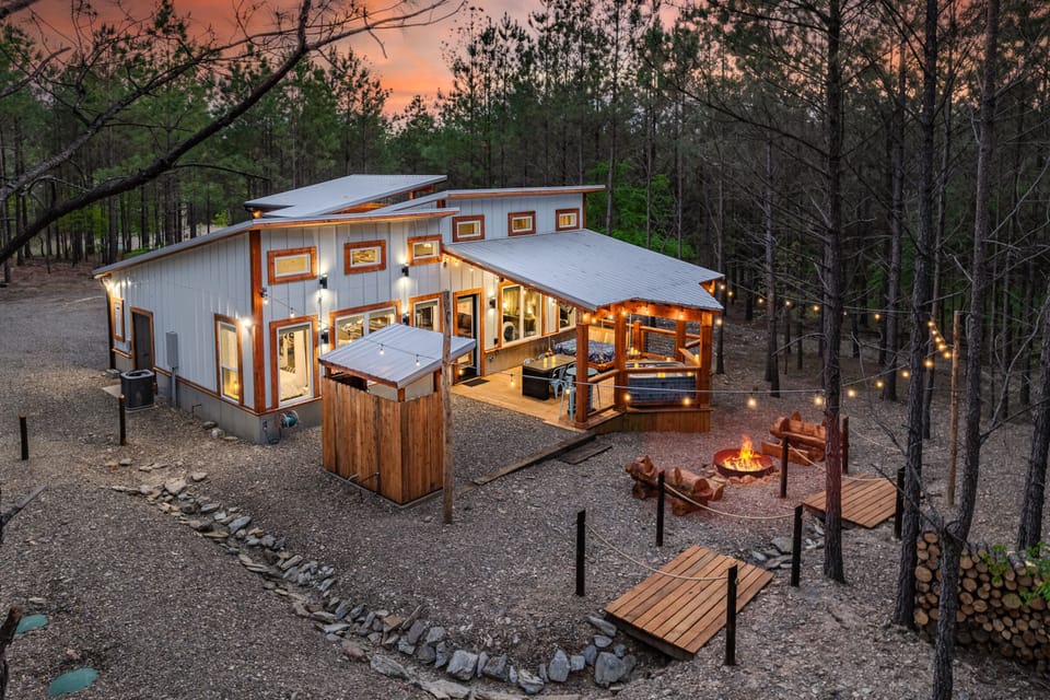 Modern rustic cabin illuminated at dusk in the pines