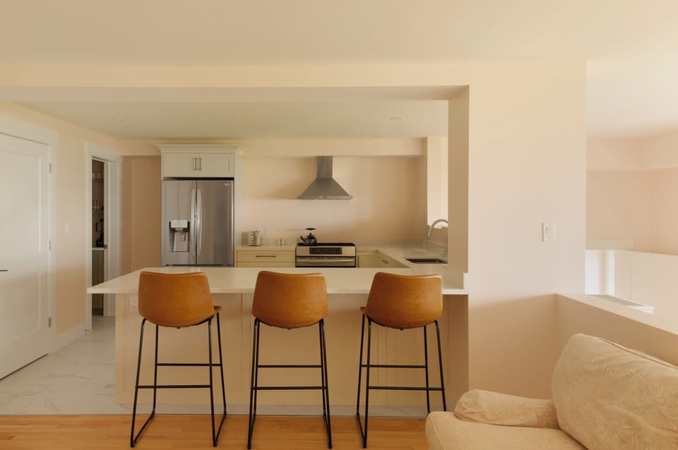 View from living room into the kitchen with bar stool seating, bathroom door and pantry on the left.