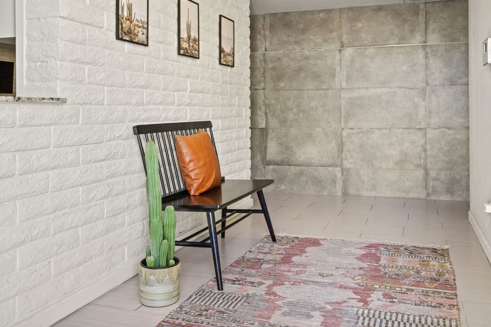 a cute loveseat chair in the entrance to comfortably put on or take off shoes