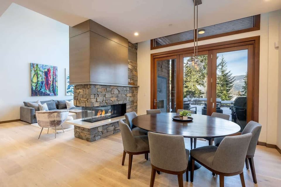 - Dining area with fireplace views and seating for family gatherings  
- Large glass doors open to patio and nature beyond  
- Stylish space merging comfort and warmth in every detail  