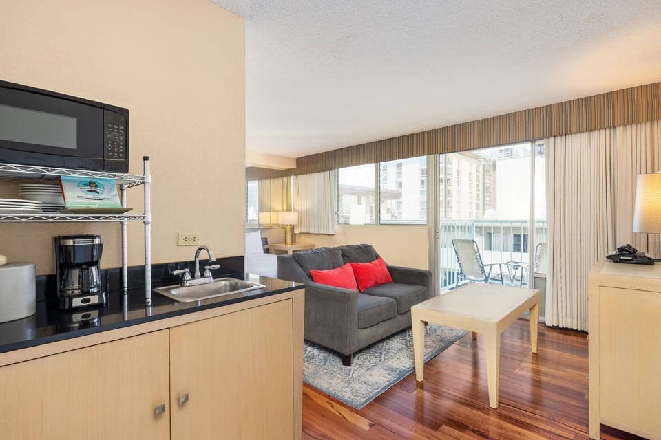 Picture yourself unwinding on the cozy sofa after a day of adventure, with sunlight streaming through your private balcony. Your fully equipped kitchenette makes morning coffee effortless, while warm wood floors invite you home.