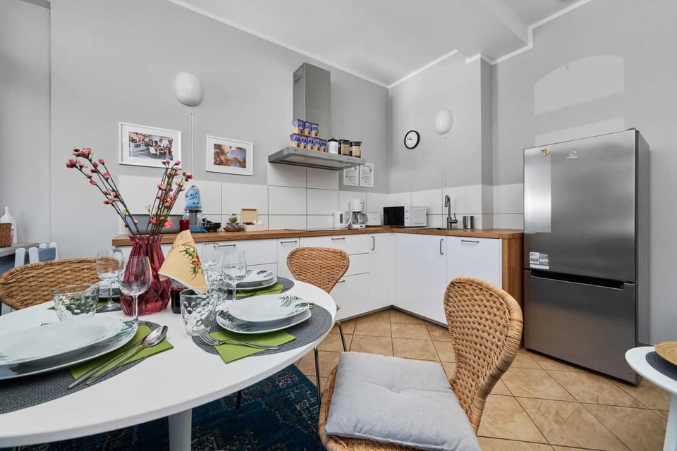 A modern kitchen with white cabinets, tiled floors, and a small round table with chairs.