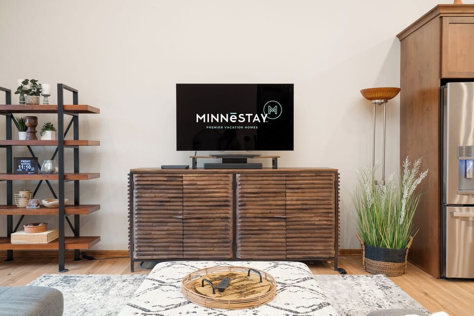 Relax in your stylish living space with warm wood tones, modern furnishings, and entertainment setup perfect for cozy evenings.