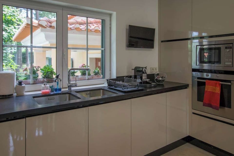 Modern kitchen with dark countertops and garden views — Villa Buganvilia III, holiday villa in Herdade de Aroeira