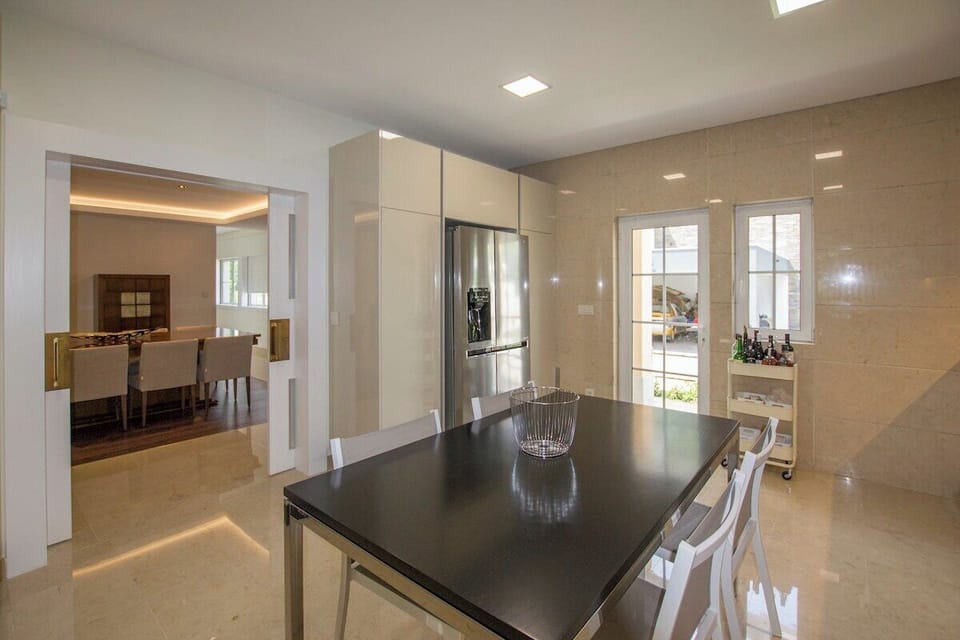 Modern open-plan kitchen with black island and stainless steel appliances — Villa Buganvilia III, luxury holiday villa in Herdade de Aroeira