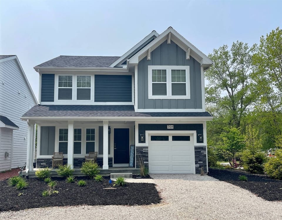 This modern home welcomes you with a charming front porch, clean blue and white siding, and stylish stone accents.