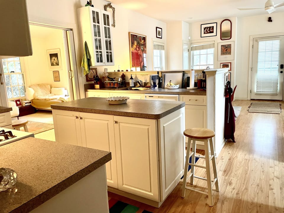the kitchen sits between sun room, living space, and bedroom downstairs