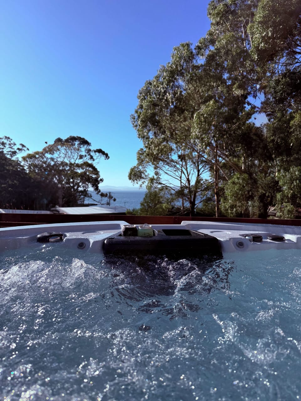 Outdoor spa heated to 40 degrees Celsius with water view. 