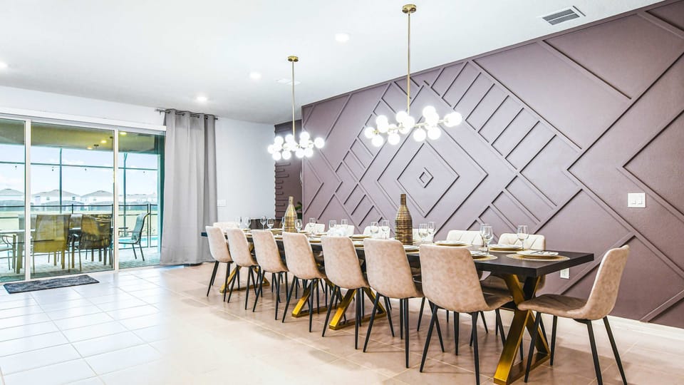 Stylish dining space with bold accent wall, elegant lighting, and seating for 14.