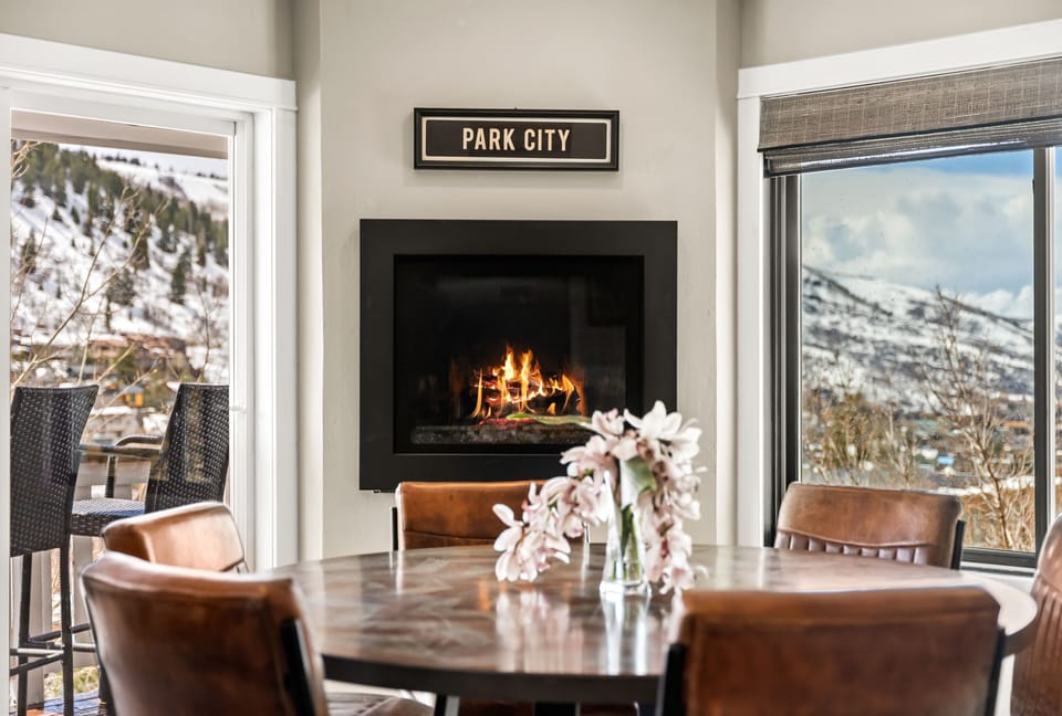 - Dining table with fireplace and large scenic views  
- Windows frame snowy slopes for perfect mealtime vibe  
- Cozy mountain dining space in the heart of Park City