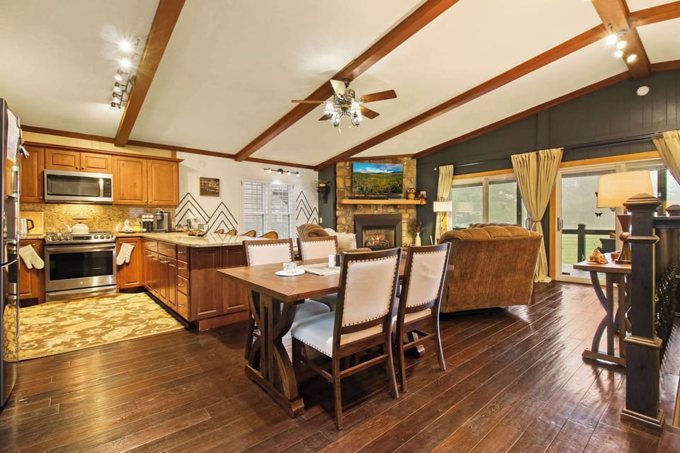 Warm and inviting, this open-concept living space features a fully equipped kitchen, a cozy stone fireplace, and charming wood-beam ceilings—perfect for gathering with loved ones or enjoying a quiet evening in.