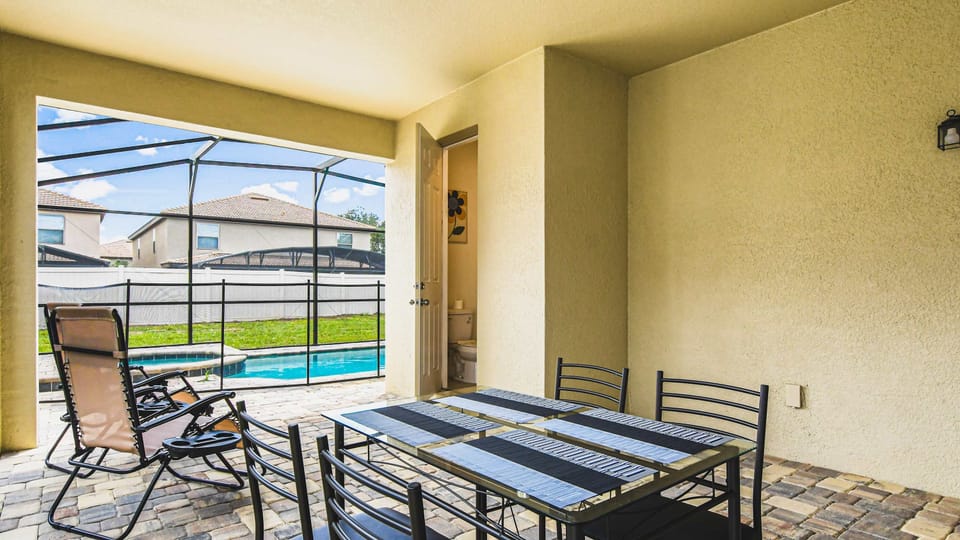 Outdoor dining by the pool with a private bathroom and sunny screened lanai.