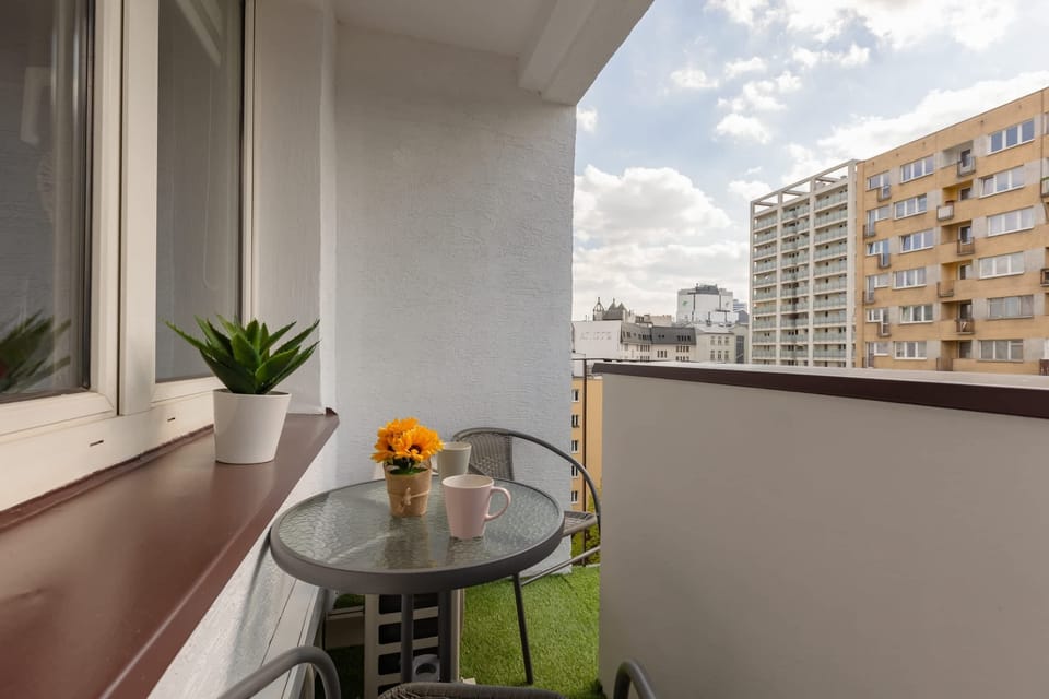 A view from the balcony overlooking city buildings and tree-lined streets, providing a mix of urban and natural elements.