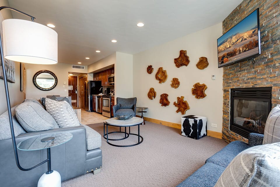 Relax in your thoughtfully designed living space, where warm wood art meets cozy seating by a crackling fireplace.