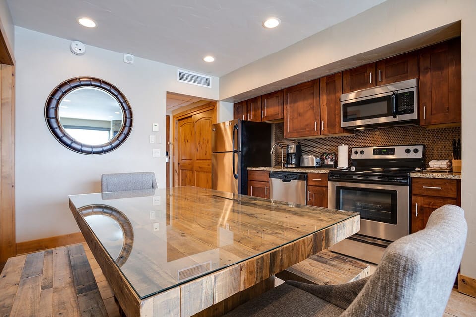 Your fully equipped kitchen features rich wood cabinets, granite counters, and a stunning glass dining table perfect for memorable meals together.