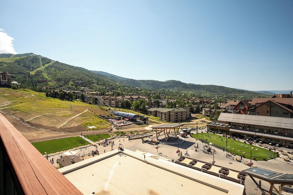 Mountain resort village sprawls below forested peaks, with recreational facilities and lodges creating an alpine community setting.
