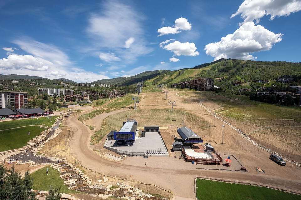 Aerial view of mountain resort area showcasing ski slopes, base facilities, and surrounding mountain landscape with residential buildings.