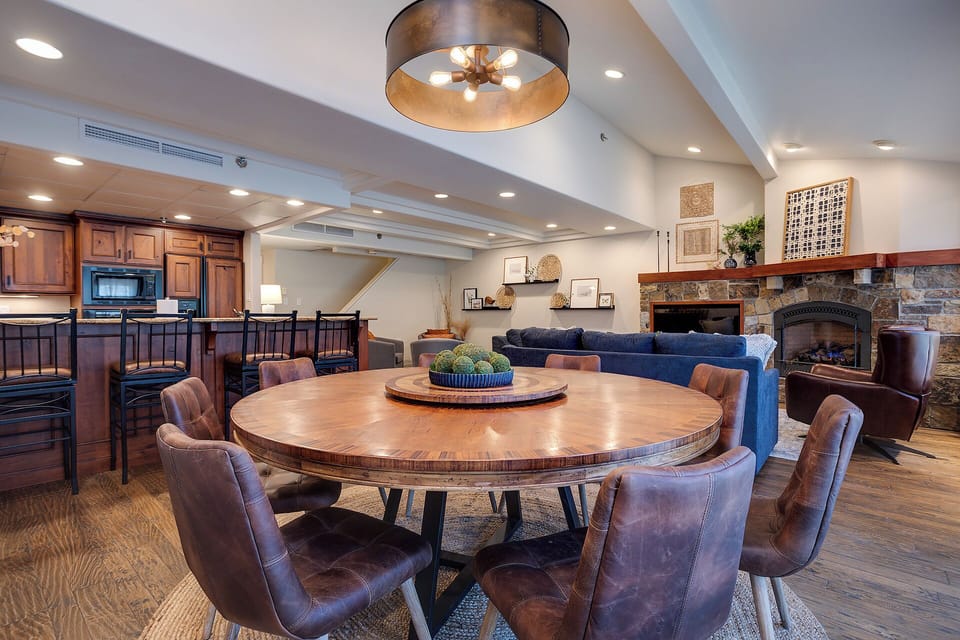 Gather around your stunning round dining table for memorable meals, with a cozy fireplace and kitchen creating the perfect atmosphere.