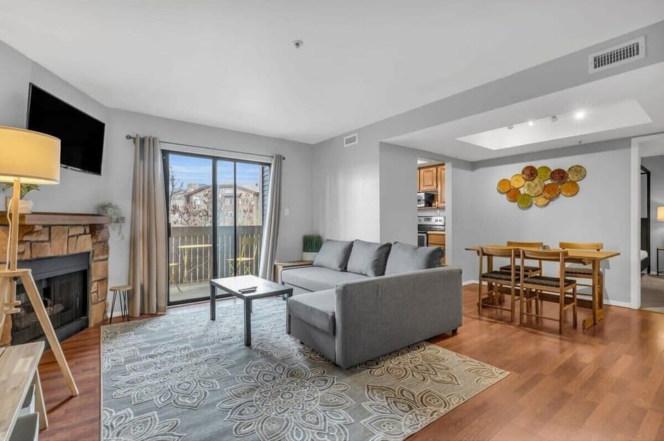 The living room is a bright light-filled room with a cozy fireplace and access to an outdoor balcony.