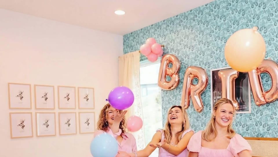 Bachelorette weekend central: bedroom with patterned wallpaper and space for the whole crew to gather, balloon decorations included