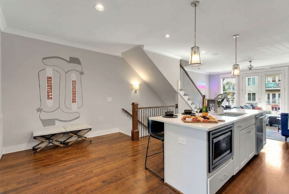 Dining table with a built-in microwave and pendant lights over the kitchen island, plus a Nashville-inspired boot mural to set the mood