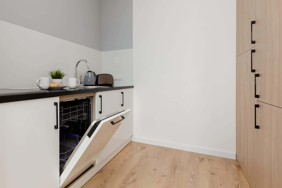 Kitchenette with electric cooktop, electric kettle, microwave, dishwasher, refrigerator with freezer, toaster and washing machine.