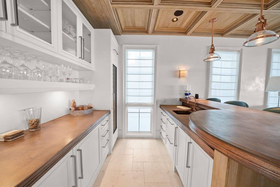 Your stylish galley kitchen features warm wood countertops, crisp white cabinetry, and charming copper pendant lights—perfect for preparing meals together.