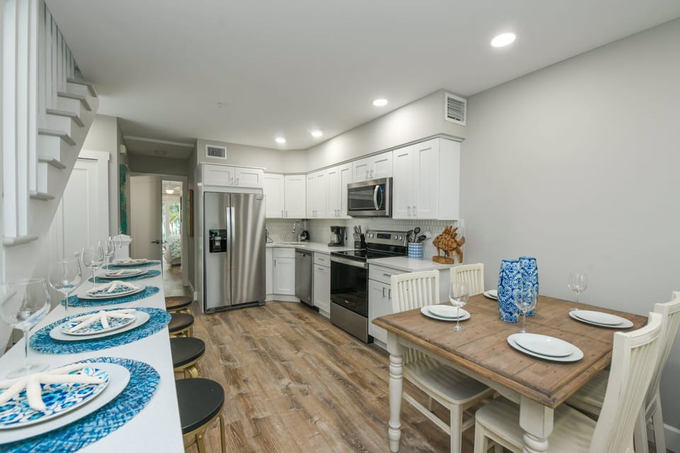 The fully equipped kitchen offers stainless steel appliances, ample prep space, and a dining table ready for shared meals.