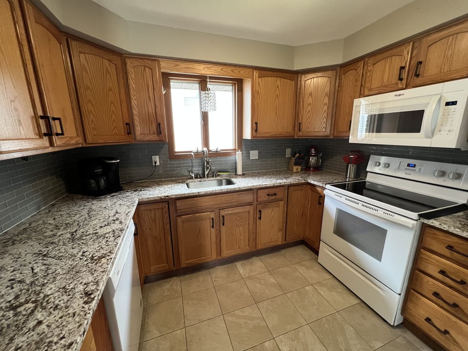 Kitchen with fridge, oven, microwave, coffee maker, crockpot, and essentials.